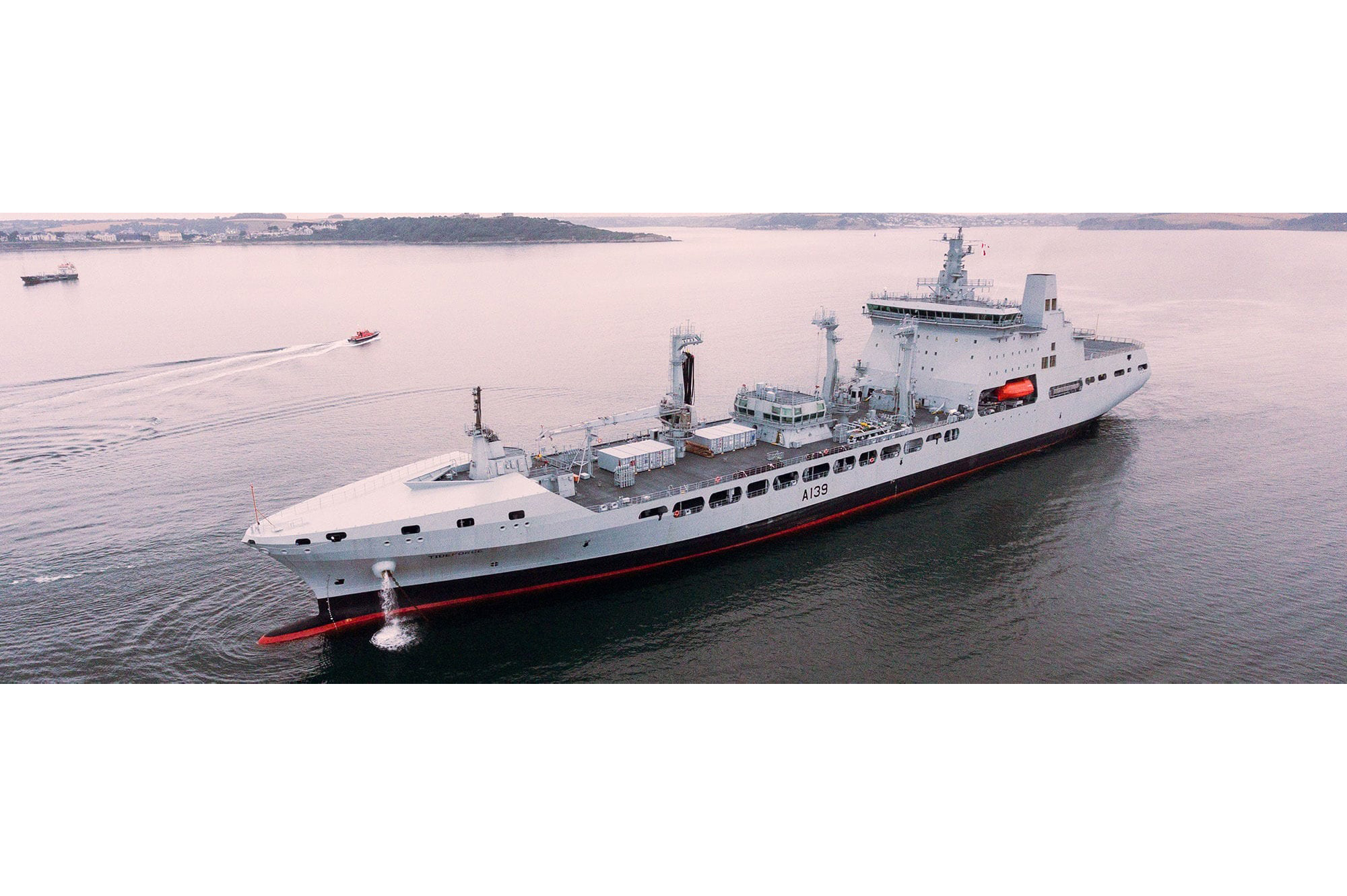 A long grey ship in still harbour waters