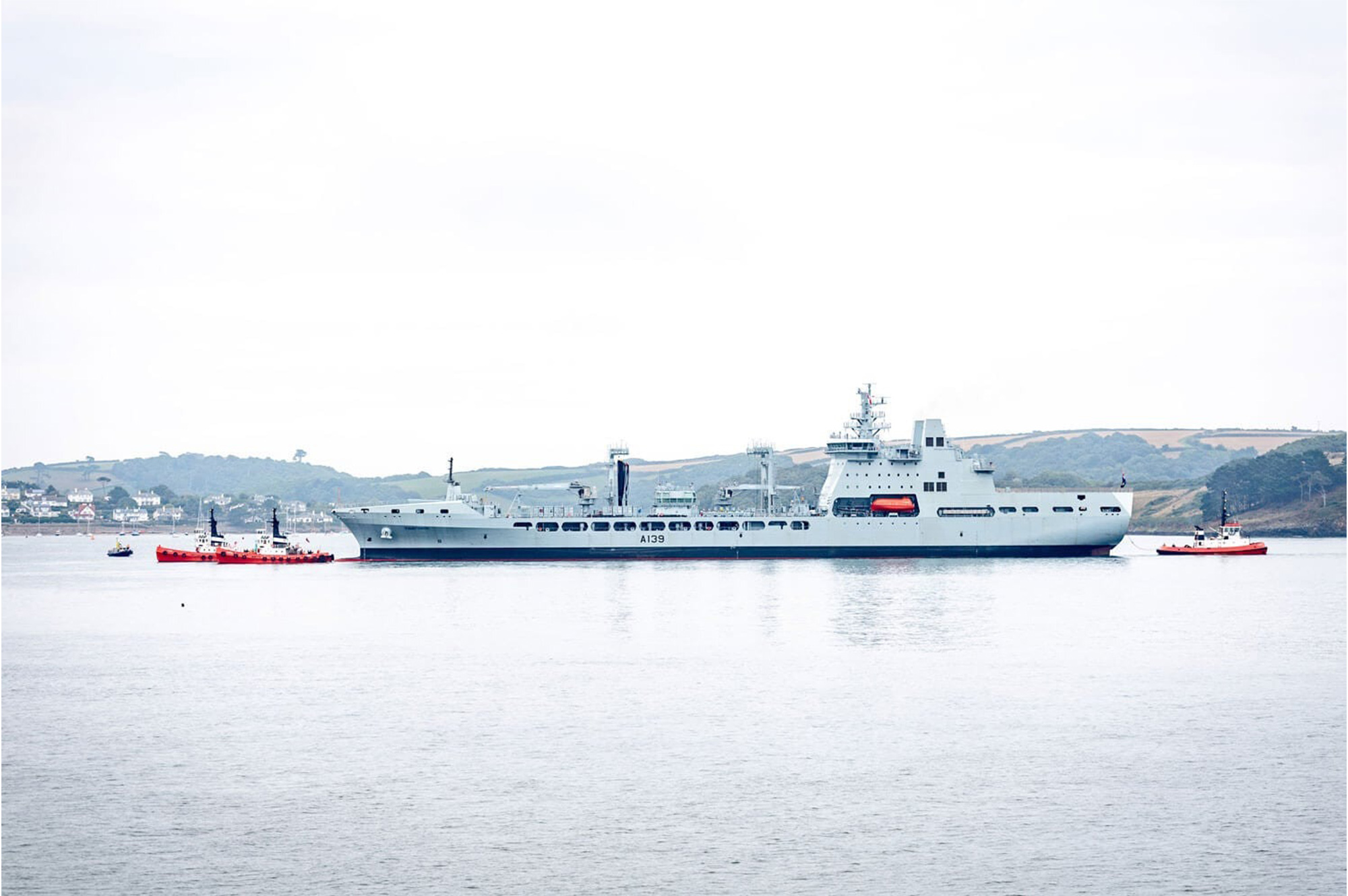 A long grey ship in still harbour waters